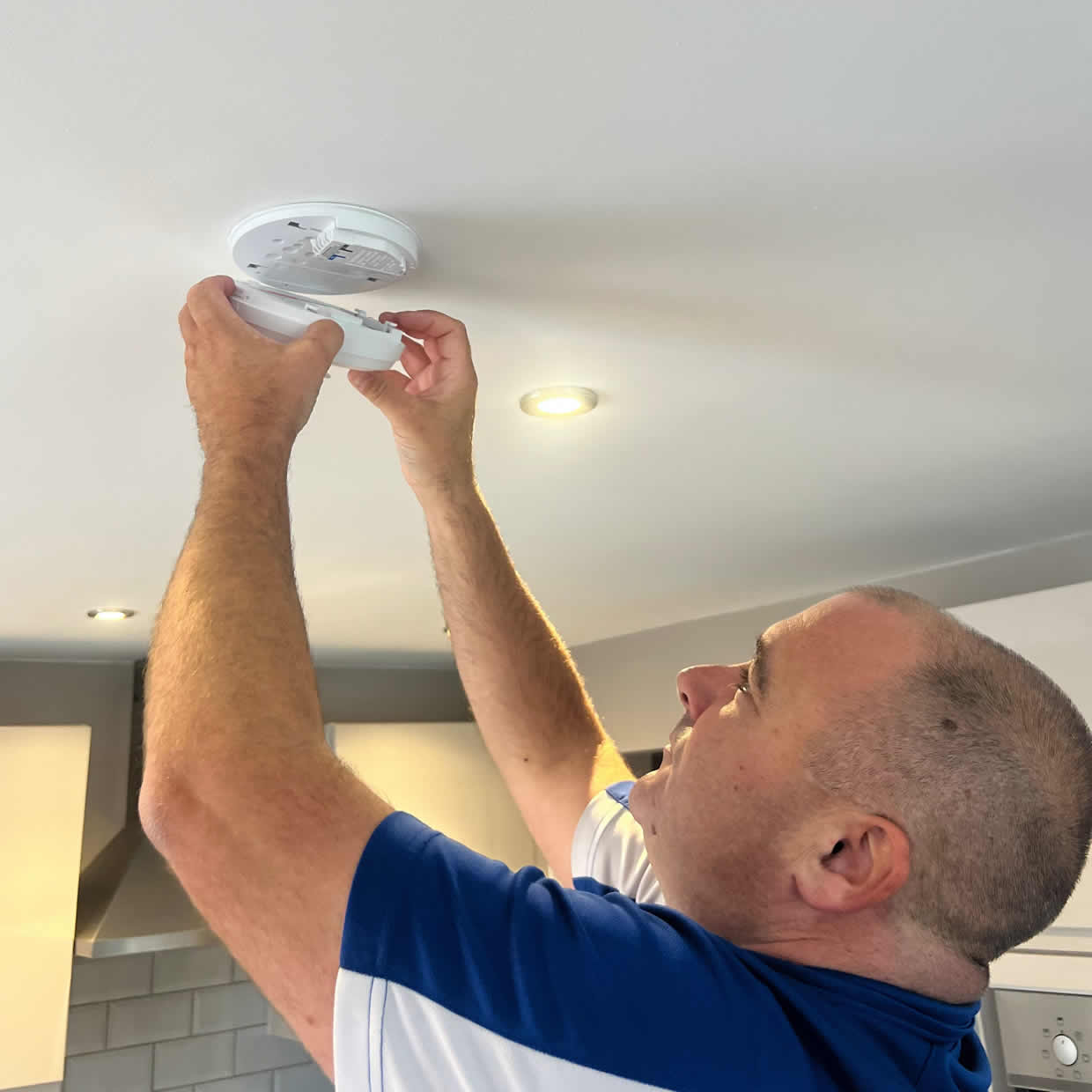 Smoke alarm installer diagnosing and fitting an alarm in a Smethwick property